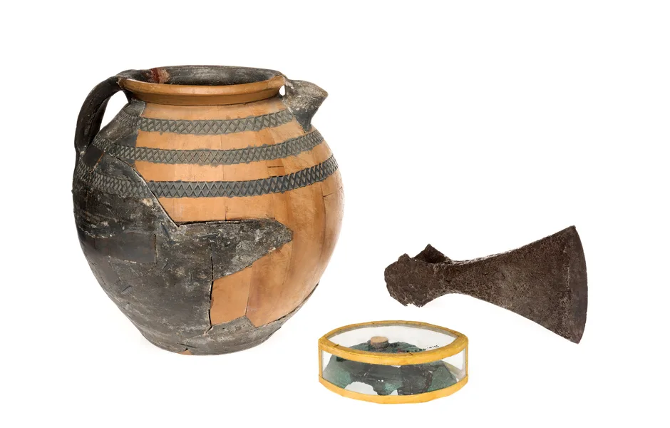 Kreamikvas, yxhuvud och bronsliknande föremål i en ask